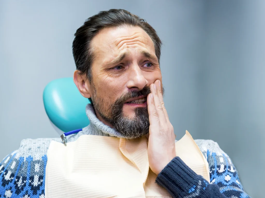Mature man seeing an emergency dentist for tooth pain