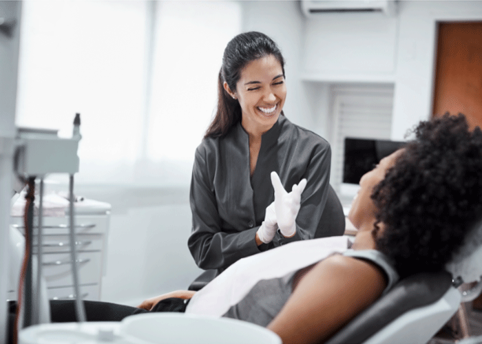 Stock photo of a dental hygienist laughing with a female patient.