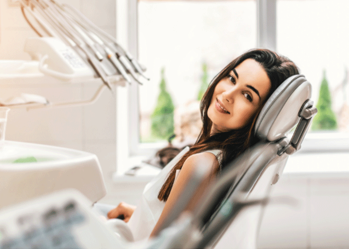 Stock photo of a woman sitting in a dental chair smiling.